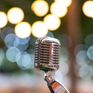 A silver microphone sits against a backdrop of lights.