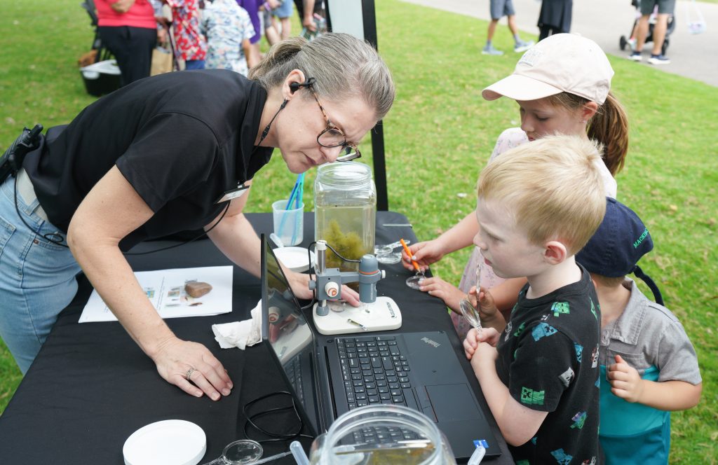 A teacher helps a child understand a laptop.