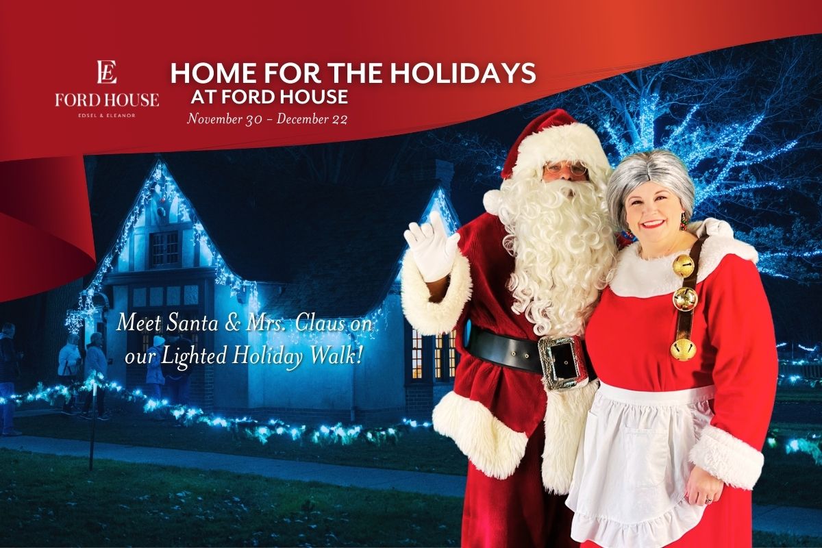 Image of Santa and Mrs. Claus standing in front of the Playhouse with lights.