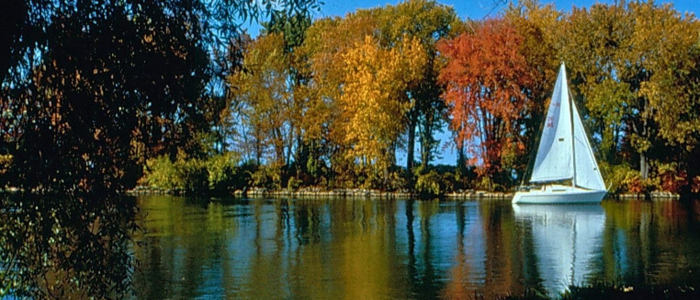 Autumn shoreline at Ford House with colorful fall trees reflected along Ford Cove, featured on the Autumn Shoreline Guided Tour.
